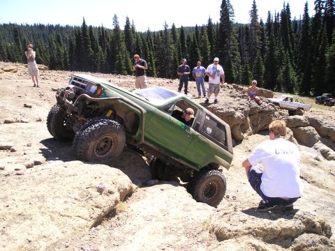 1989 Ford Bronco - A modified 1989 Ford Bronco navigates a challenging rocky trail with spectators watching.