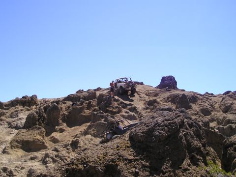 1989 Ford Bronco - Off-road vehicles tackle challenging rocky terrain on a sunny day.