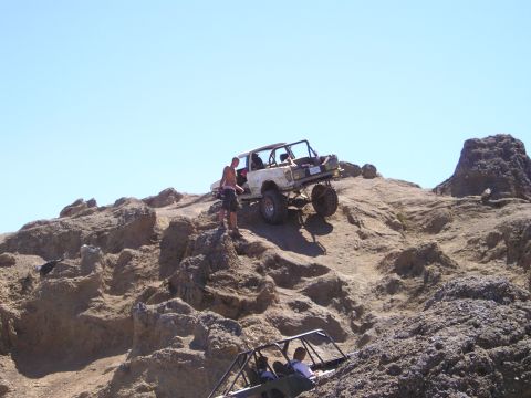 1989 Ford Bronco - Off-road vehicles navigate a challenging rocky terrain under a clear blue sky.