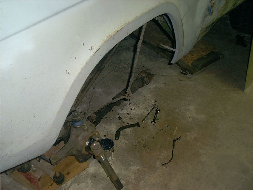 close-up of vehicle's front suspension with tools on the ground