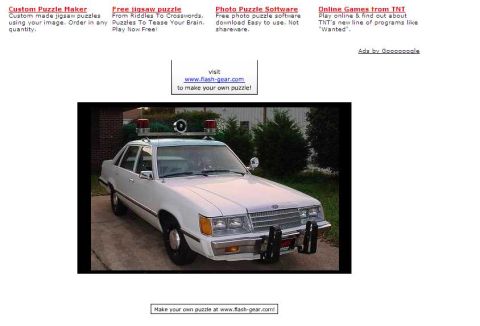 2000 Ford Crown Victoria - This police car features a light bar on the roof and a distinctive 1980s body style.