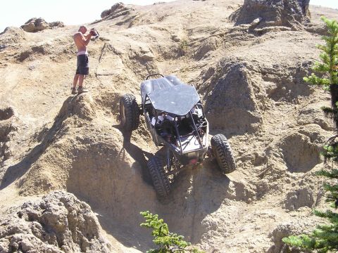 1989 Ford Bronco - Off-road buggy tackles a challenging rocky incline with a photographer observing from above.