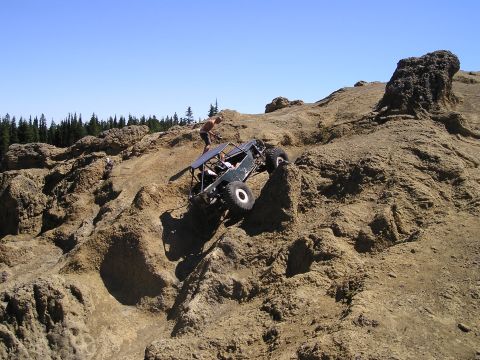 1989 Ford Bronco - A custom off-road vehicle navigates a challenging rocky terrain on a sunny day.