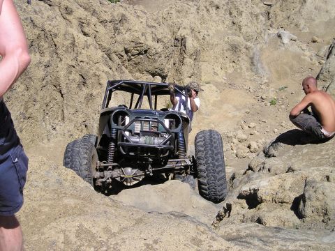 1989 Ford Bronco - A custom-built off-road buggy tackles a challenging rocky trail with two people observing.