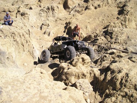 1989 Ford Bronco - A custom off-road buggy navigates a challenging rocky incline during an event.