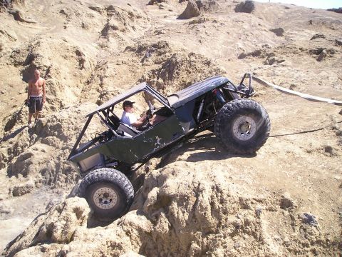 1989 Ford Bronco - Custom off-road buggy tackles a steep, rocky terrain with a spectator watching.