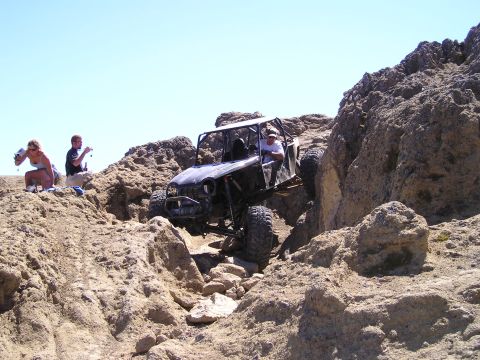 1989 Ford Bronco - A custom off-road buggy navigates a challenging rocky trail with spectators watching.