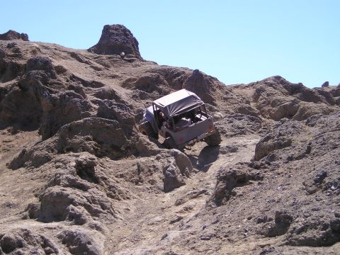 1989 Ford Bronco - An off-road vehicle navigates a challenging rocky trail, demonstrating its capability on uneven terrain.