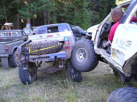 1989 Ford Bronco - Off-road vehicles are entangled in a difficult situation with one truck's rear tire resting on the other.