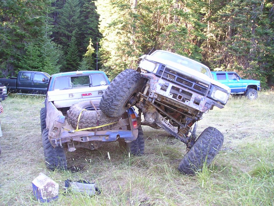 Two off-road trucks stuck in the mud, one on top of the other