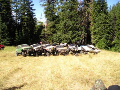 1989 Ford Bronco - A row of about eight built trail rigs, lifted mini-trucks and cut-down 4x4s in green, white, blue and tan, several with roll cages and tube…