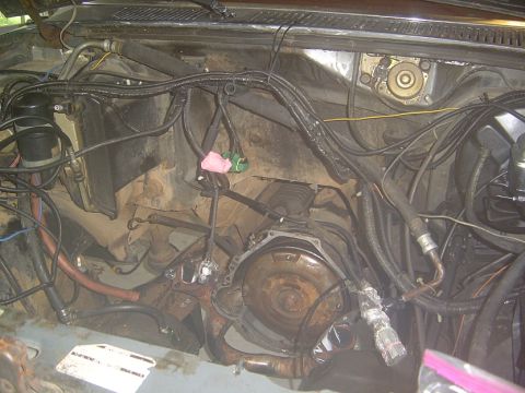 1986 Ford Bronco - The engine bay of a vehicle, showing the transmission and a complex network of wiring and hoses.