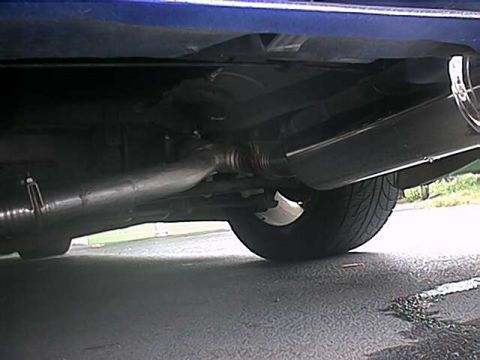 1993 Ford Probe - The underside of a blue vehicle, focusing on the exhaust system and a rear tire.