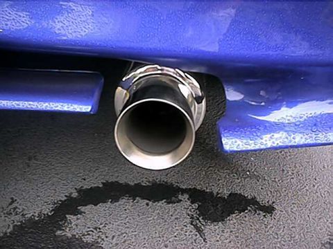 1993 Ford Probe - Chrome exhaust tip on a blue vehicle, with a spill on the asphalt below.
