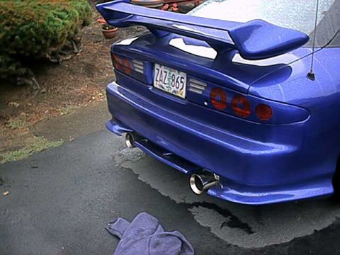 1993 Ford Probe - The rear of a blue sports car is visible, a large spoiler and dual exhaust pipes.