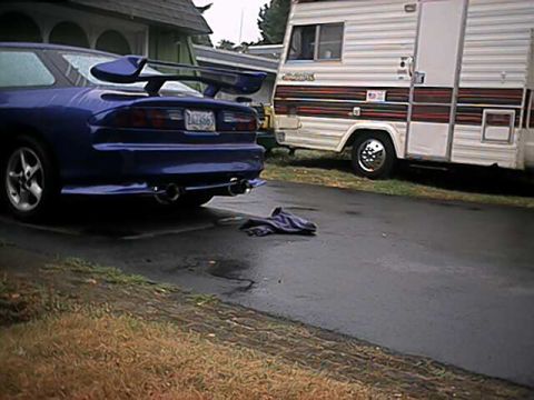1993 Ford Probe - Rear view of a blue 1993 Ford Probe, a prominent spoiler and dual exhaust pipes, parked next to an RV.