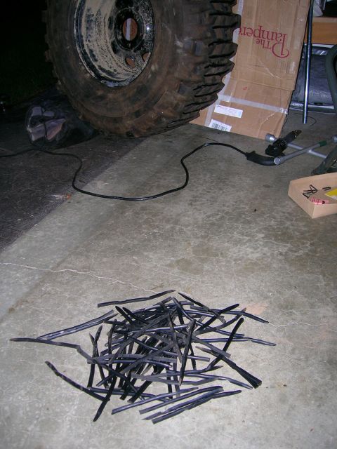 2003 Jeep TJ - Pile of rubber strips and a large tire on a concrete floor.