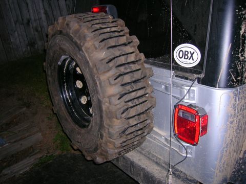 2003 Jeep TJ - A spare tire is mounted to the rear of a Jeep, with an OBX sticker visible on the rear window.
