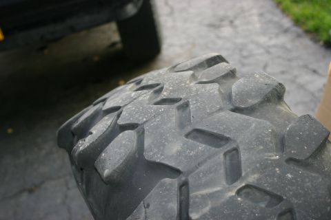 2003 Jeep TJ - A close-up of a tire's aggressive tread pattern is visible, with another vehicle's wheel in the background.