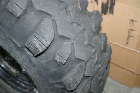 2003 Jeep TJ - The aggressive tread pattern of a tire is visible, with the word 'Kitchen' handwritten on a cardboard box in the background.