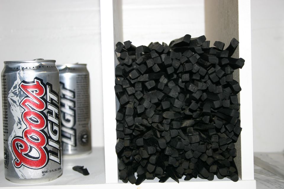 Two Coors Light cans next to a white shelf filled with black charcoal pieces