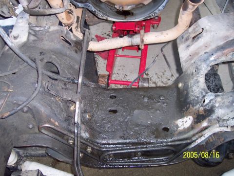1985 Ford Bronco - The engine bay of a 1985 Ford Bronco is shown with a red jack supporting the transmission during an apparent rebuild.