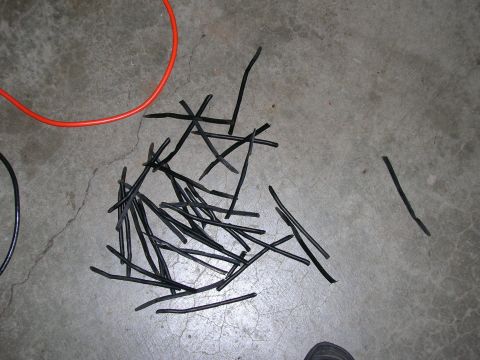 2003 Jeep TJ - Scattered black rubber pieces and a coiled orange cable lie on a cracked concrete surface.