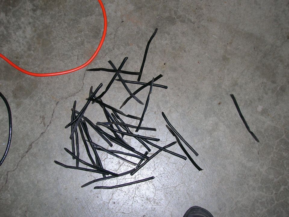 Pile of black rubber strips and an orange cable on a concrete floor