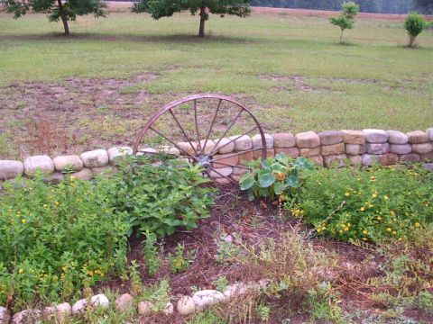 1966 Ford Ranchero - A rustic wagon wheel is incorporated into a garden landscape with a stone retaining wall.