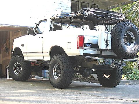 1995 Ford Bronco - This lifted Ford Bronco features a removable soft top and a large spare tire on the back.