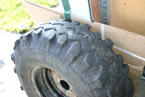 2003 Jeep TJ - A single off-road tire is shown, leaning against a cardboard box in what appears to be a garage or storage area.