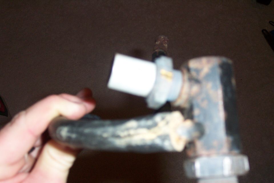 Part held by hand, white plastic cap on metal rod, rust on metal