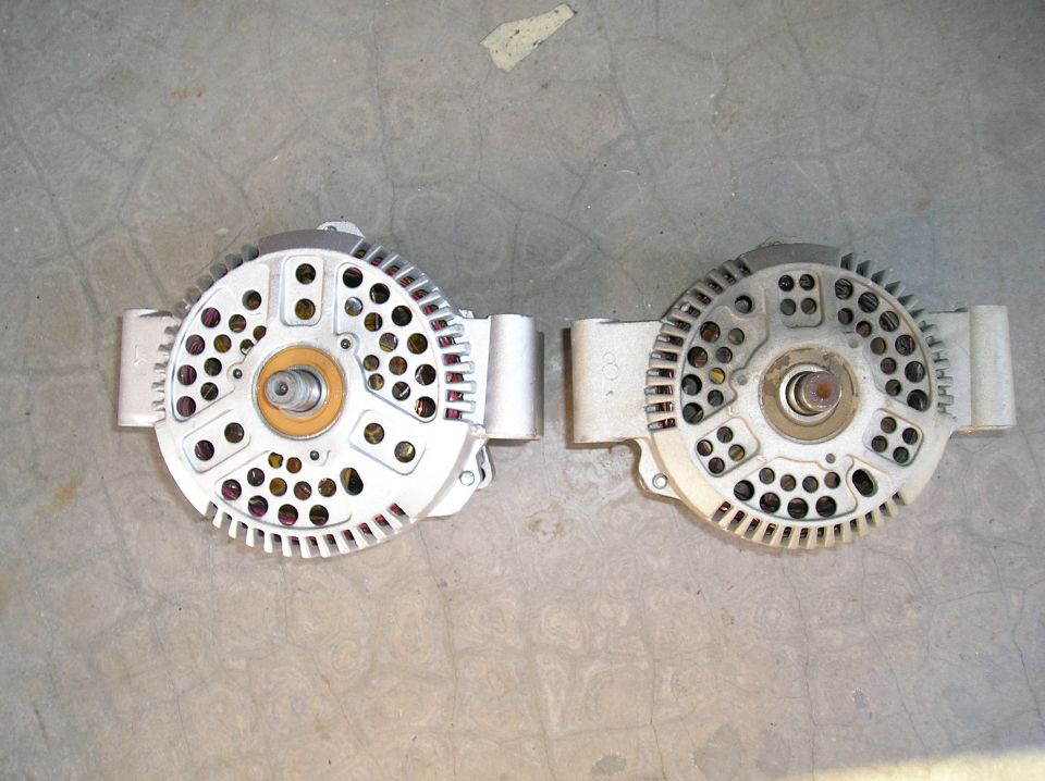 Two Ford alternators without pulleys side by side on a concrete floor