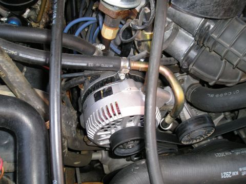 1993 Ford Bronco - Close-up view of an alternator, belt, and various hoses within an engine compartment.