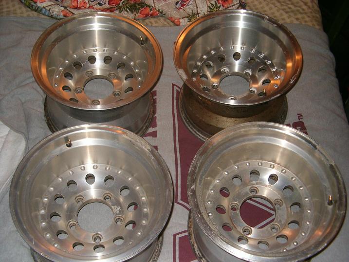 four aluminum alloy wheels with multiple lug nut holes and a center bore
