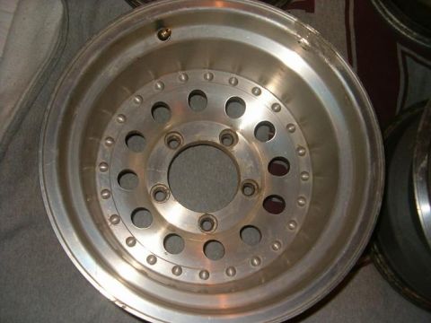 1995 Ford Bronco - Close-up of a single aluminum alloy wheel with a multi-hole design and visible wear.