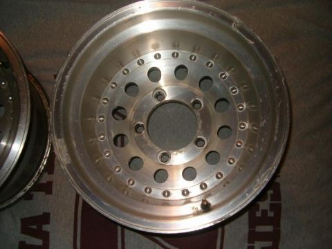 1995 Ford Bronco - Two aluminum alloy wheels are shown up close, resting on a patterned surface.