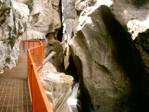 1996 Ford Probe - Walkway through a narrow canyon with a waterfall in the background. The walkway has a metal grate surface and orange railings.