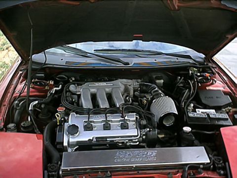 1996 Ford Probe - The engine bay of a red car is shown with the hood open, revealing the V6 engine and various components.
