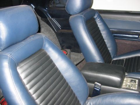 1987 Ford Thunderbird - Interior view of blue and black bucket seats and a center console.