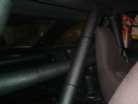 1995 Ford Probe - The interior of a vehicle shows a roll cage and a racing seat, with some items visible in the background.