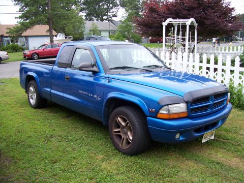 1971 Ford Mustang - A blue Dodge Dakota R/T pickup truck is parked on a grassy lawn in front of a white picket fence.