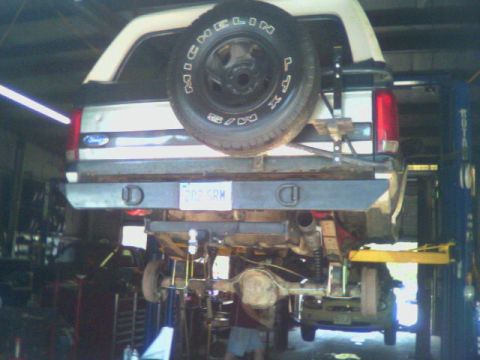 1993 Ford Bronco - The rear of a 1993 Ford Bronco is shown lifted in a garage, undergoing modifications.