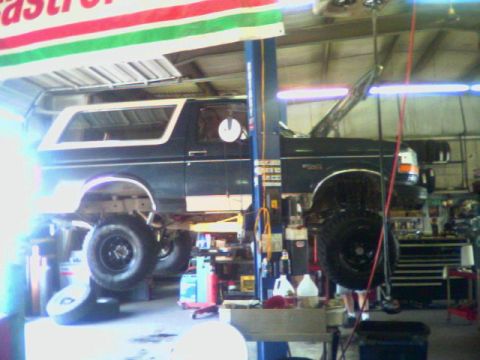 1993 Ford Bronco - A 1993 Ford Bronco is raised on a lift in a garage, undergoing service with its hood open.