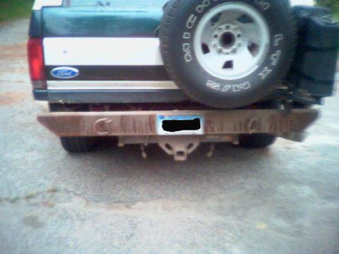 1993 Ford Bronco - Close rear view of a green Ford SUV fitted with a bare, surface-rusted fabricated steel rear bumper with D-ring tabs and a receiver hitch,…