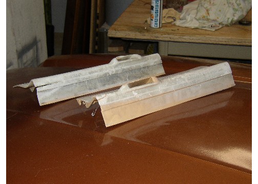 Two unfinished car trim pieces on a brown car hood