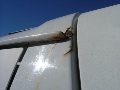 1993 Ford Bronco - Rust is visible on the edge of a white vehicle panel under a clear blue sky.