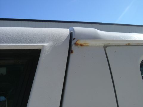 1993 Ford Bronco - The seam between two body panels on a white SUV shows signs of rust.