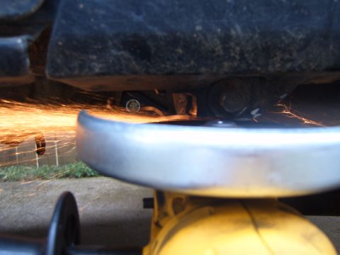 1988 Ford Bronco - Metal is being cut with an angle grinder underneath a vehicle, creating a shower of sparks.
