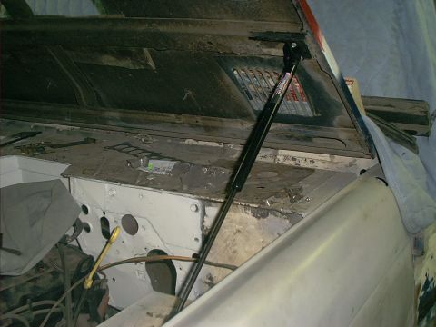 1990 Ford Bronco - The engine bay of a 1990 Ford Bronco is visible with the hood propped open, revealing the firewall and engine components.